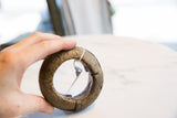 Hand holding the thick antique bronze bracelet to display its scale and textured profile.