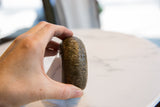 Antique African bronze bracelet held in hand, showing its substantial form and patina.