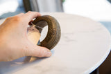 A hand holding the thick antique bronze bracelet, highlighting its size and geometric engravings.