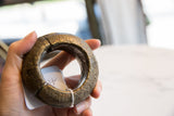 The substantial scale of a thick, antique African bronze bracelet shown held in hand.
