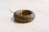 Angled profile of a thick, antique African bronze bracelet with geometric, hand-etched detailing.