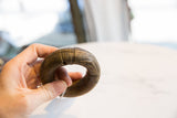 Antique African bronze bracelet held in hand, highlighting its substantial size and aged patina.