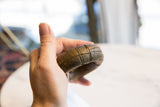 A hand holding the thick antique bronze bracelet, showing its size and etched patterns.