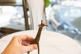 Hand holding a mid-century African bronze alloy giraffe, showcasing its unique form and aged patina.
