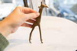 Hand-held vintage African bronze alloy giraffe, showing handmade texture and short tail.