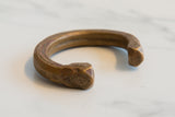 Detailed craftsmanship of etched patterns on an antique African bronze snake cuff.