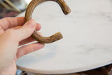 Antique African snake cuff bracelet held to show its open C-shape and scale.
