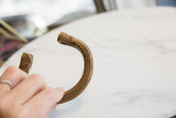 Hand-held view of an antique snake cuff bracelet showing its etched patterns and warm patina.