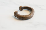 Coiled texture and smooth, rounded ends of an antique African copper snake cuff bracelet.