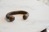 Side view of the antique African snake cuff showing the ridged body and smooth, heavy ends.