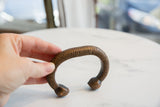 Hand demonstrating the size and ribbed texture of an antique copper snake cuff.