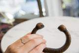 The open shape and stylized terminals of an antique copper snake cuff.