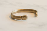 Rounded end and curved form of the antique bronze cuff bracelet with an aged patina.