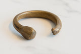 Antique African bronze snake cuff highlighting its sculpted head and rugged, aged texture.