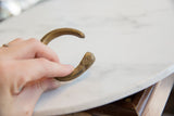 Hand holding the antique bronze snake cuff, showing its etched head and texture.