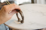 Hand holding an antique snake cuff bracelet to demonstrate its scale and C-shape.