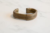 Side profile of a handcrafted African bronze cuff showing its aged gold patina and texture.