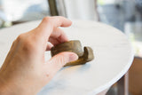 Hand holding the antique African cuff, displaying its handcrafted texture and aged bronze patina.