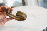 Etched braided design and time-worn gold patina on the end of an antique bronze cuff.