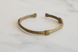 The handcrafted form and time-softened patina of a vintage African bronze cuff.