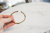 Vintage African bronze cuff bracelet held in hand to show its scale.