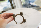 Vintage bronze cuff bracelet held in hand to display its sculptural shape and rich, aged patina.