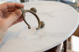 The curved C-shape and textured surface of the handmade African bronze bell cuff.