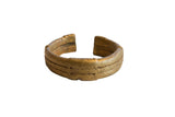 Antique African bronze cuff bracelet with a warm golden patina and incised textural details.
