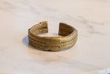 Side view of the antique African bronze cuff showing its rustic texture and golden patina.