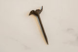 Top-down view of a collectible African bronze bird pin with a dark patina.