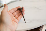 Vintage bronze bird pin held in hand, highlighting its handmade form and scale.