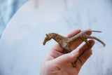 Vintage African copper horse held in hand, showing its size and slender profile.