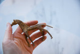 Vintage African copper horse held in a hand to show its textured patina and scale.
