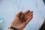 Small vintage African bronze llama held in the palm of a hand to show its scale.