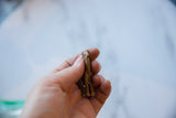 A hand holding the small bronze llama, showing its rustic, handmade texture.