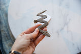Vintage African bronze snake medallion held to display its handmade texture and aged patina.