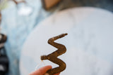 Vintage bronze snake medallion held in hand, showing its textured, handmade form.