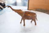 Profile view of a vintage copper elephant, showcasing its mottled patina.