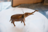 Vintage handmade African copper elephant figurine, side profile with raised trunk and aged patina.