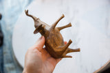 Hand holding the vintage African copper elephant, showing its textured body and abstract legs.