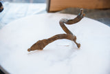 The coiled shape and textured patina of a vintage bronze snake arm cuff with rider.