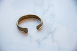 Antique African bronze cuff showing its C-shape and time-softened golden patina.
