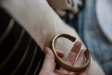 Antique bronze snake cuff bracelet held in hand, showing its substantial form and aged patina.