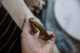 Antique African bronze cuff held in hand, showing its smooth surface and golden patina.