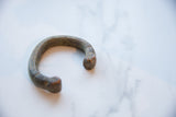 Angled view of the antique copper alloy snake cuff's curved shape and time-softened patina.