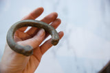 Antique African copper cuff bracelet held to show its substantial, curved form and scale.