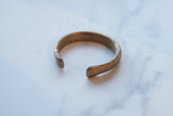 Open-ended design of an antique African copper alloy bracelet with a textured, aged patina.