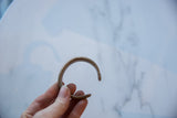 Overhead view of the antique copper alloy snake cuff, showing its open shape in hand.