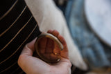 Hand holding the antique copper snake cuff, showing its thick, curved form.