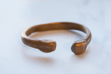 An antique copper cuff bracelet's simple C-shape and smooth, time-softened patina.
